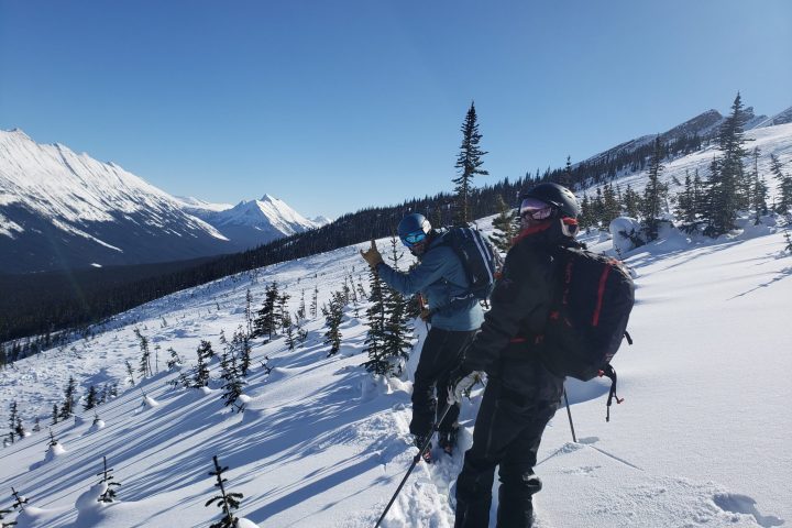 A group of people riding skis down a snow covered slope during the Robson Valley AST1 course