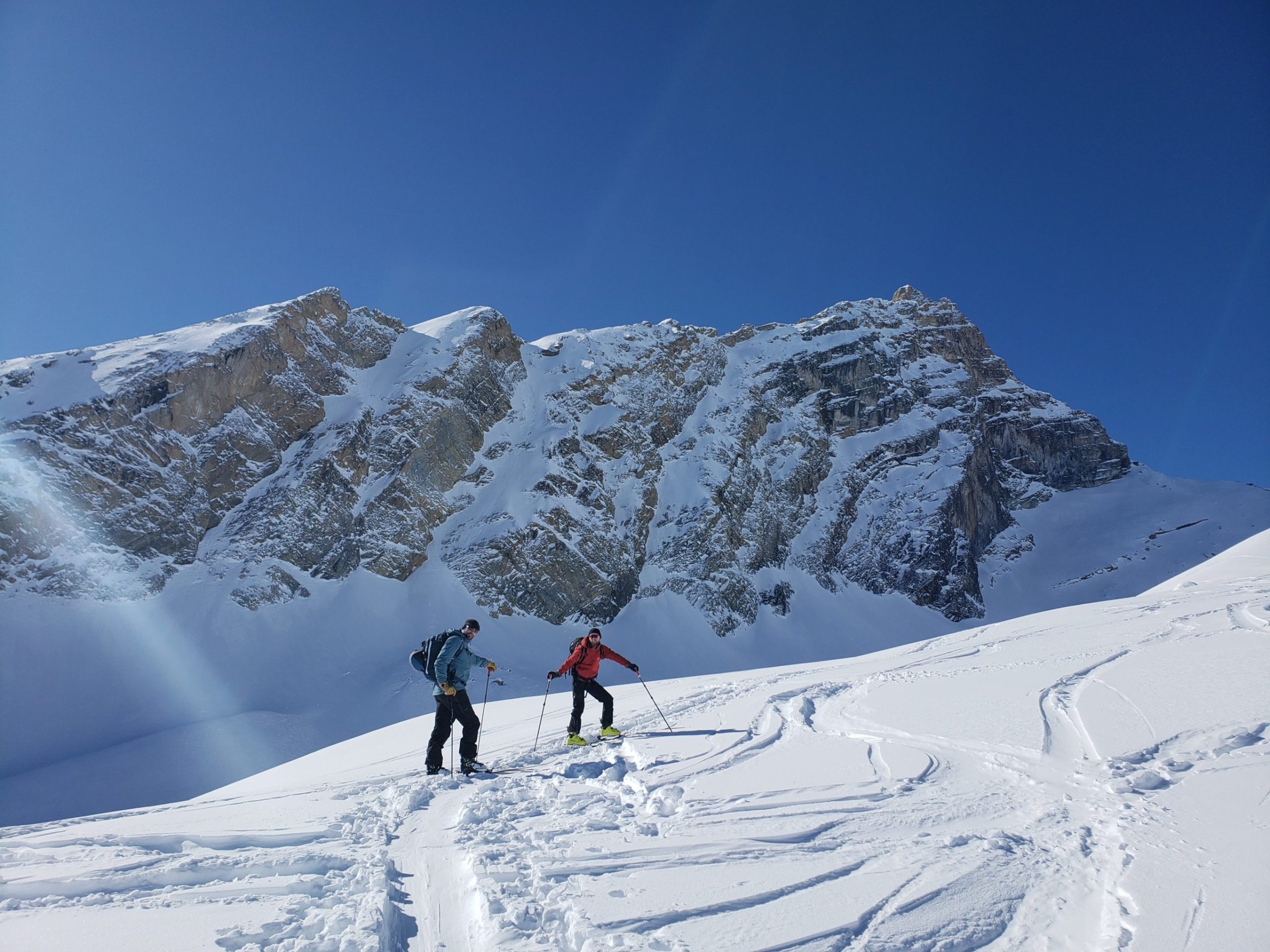 a group of people riding skis down a snow covered slope during AST1 Avalanche Skills Training 1