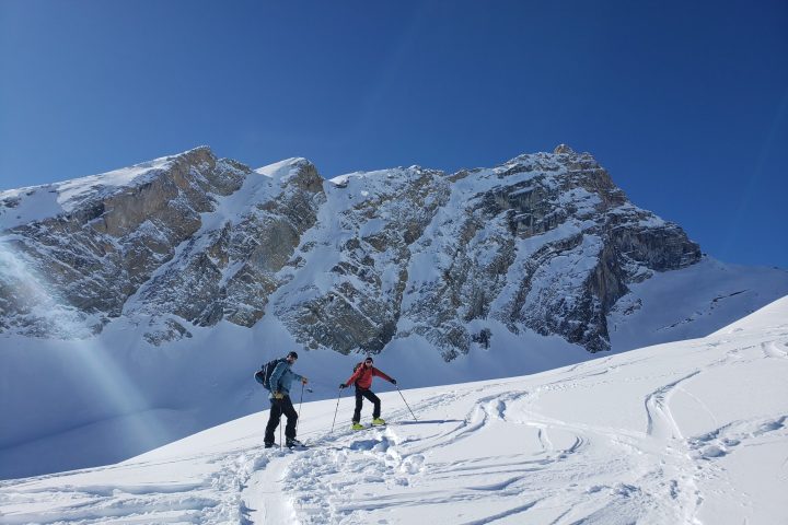 a group of people riding skis down a snow covered slope during AST1 Avalanche Skills Training 1