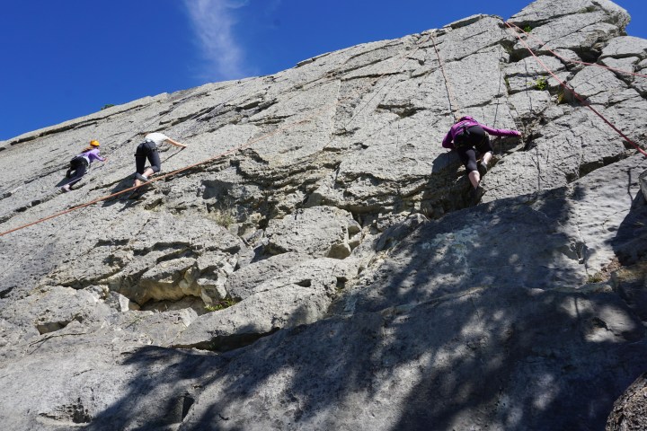 Two people rock climbing up a rock face