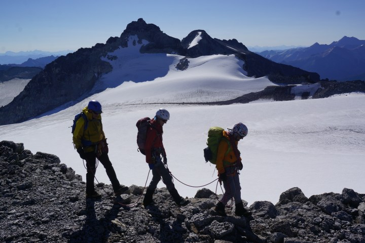 three hikers walk across mountain ridge