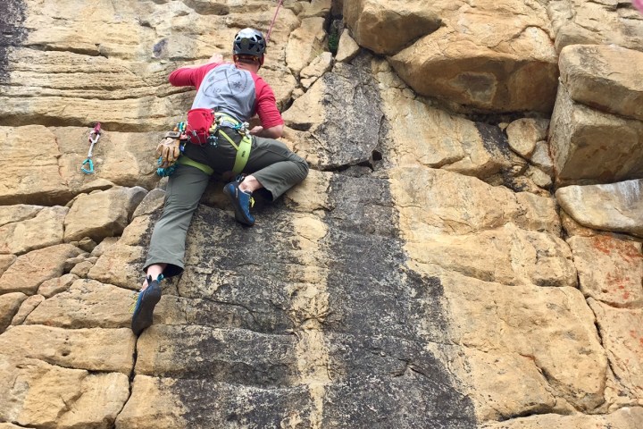 Rock climber climbing up rock wall