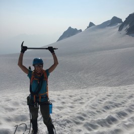 Alpine climber holding up ice pick above head