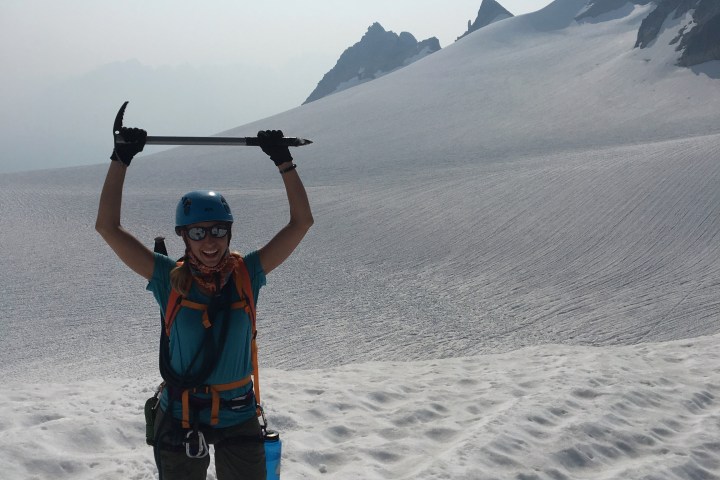 Alpine climber holding up ice pick above head
