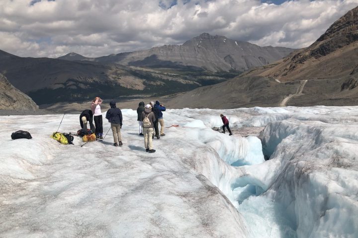 a group of people walking across a snow covered mountain