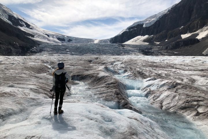 Woman hiking on the Athabasca Glacier taking in the mountain views