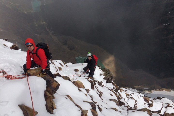 Two mountain climbers going up snow covered mountain