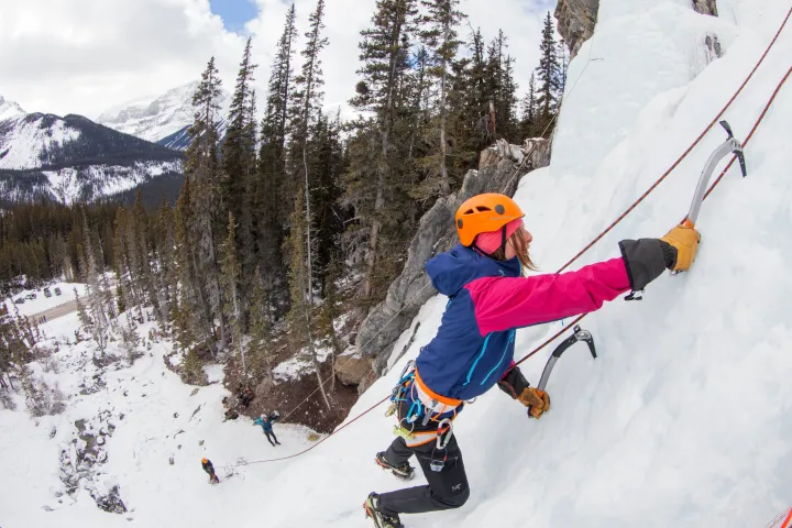 Man climbing up ice wall with ice picks